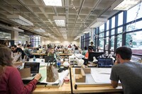 Architecture students work on drafting tables in a large classroom.