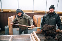 A young woman shovels compost to be used in a raingarden. 