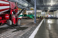 A red and white striped concrete mixer pours cement into a foundation.