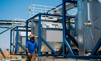  Man standing next to three stainless steel tanks used to create biochar