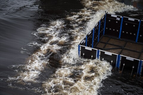 Rectangular fence system surrounded by incoming water. The enclosed portion is dry.