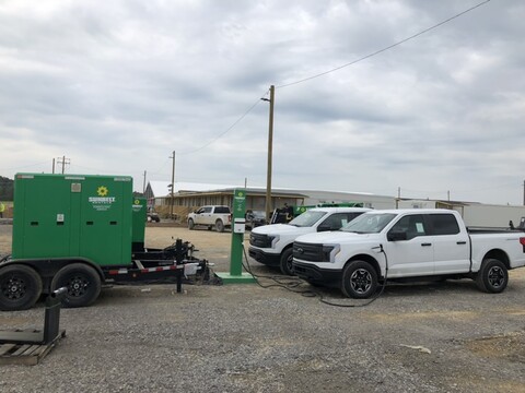 Two white pick-up trucks charging at an EV charging station.